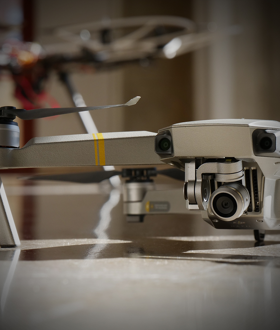 Dos drones, uno pequeño en primer plano y otro más grande detrás, posados en el suelo